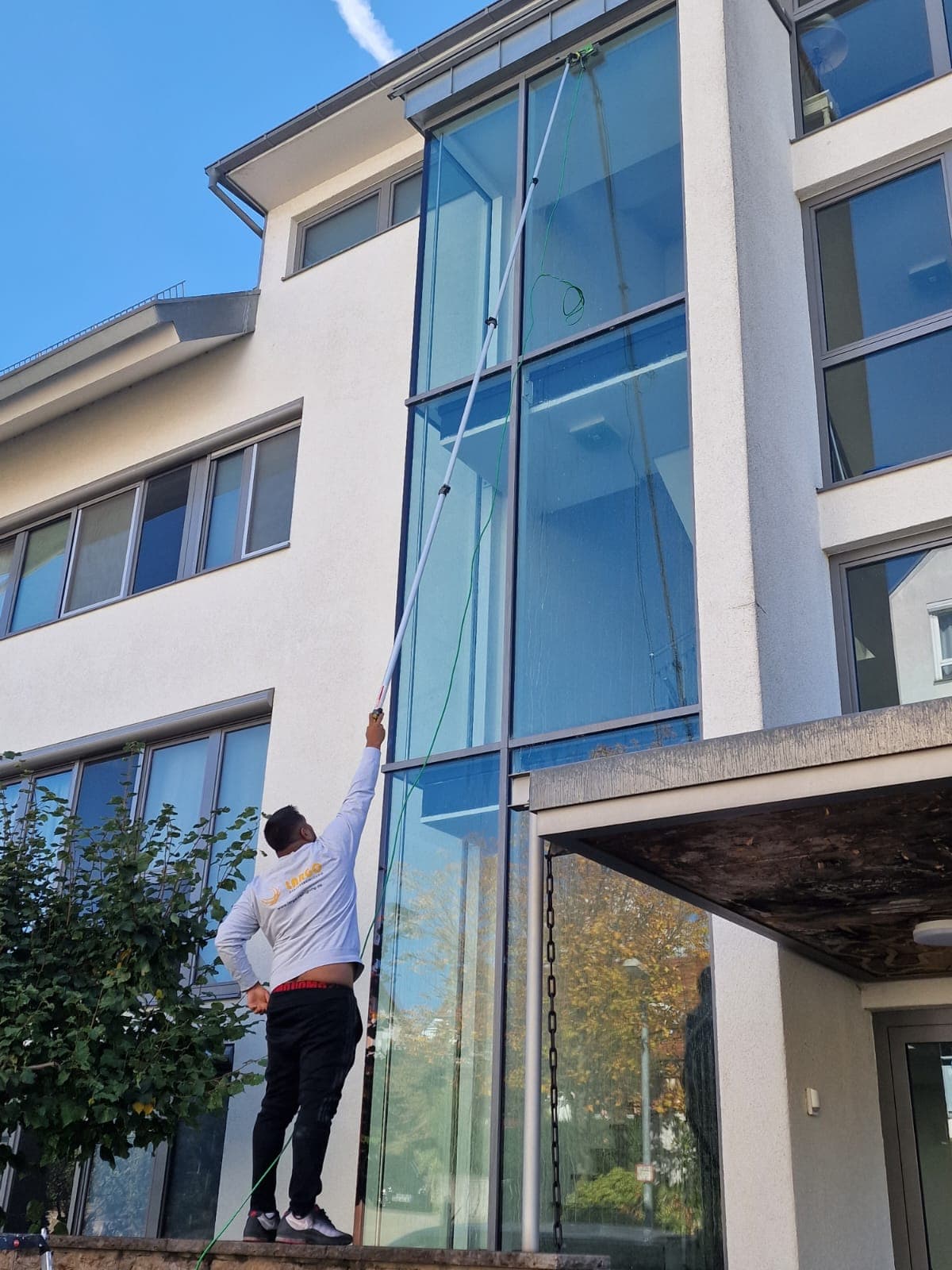 Fensterreinigung an einem Mehrfamilienhaus in Leonberg bei blauem Himmel