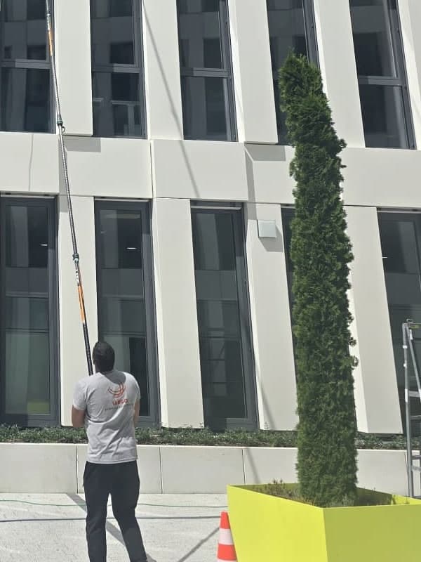 Largo-Mitarbeiter führt die Osmose-Teleskopstange an einer weißen Bürofassade